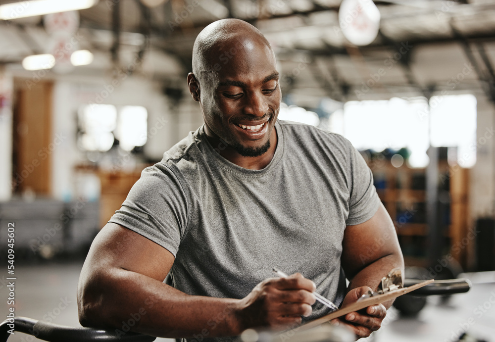 Foto Stock Gym, workout and personal trainer with checklist on clipboard  consulting for training sports in gym. Black man of muscular, active and  smiling fitness coach writing on health, wellness and exercise