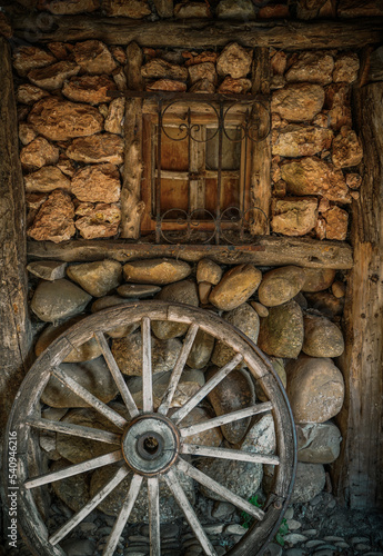 Old cart wheel, in a rustic town in Spain, Vintage style, with old stone and wood background,