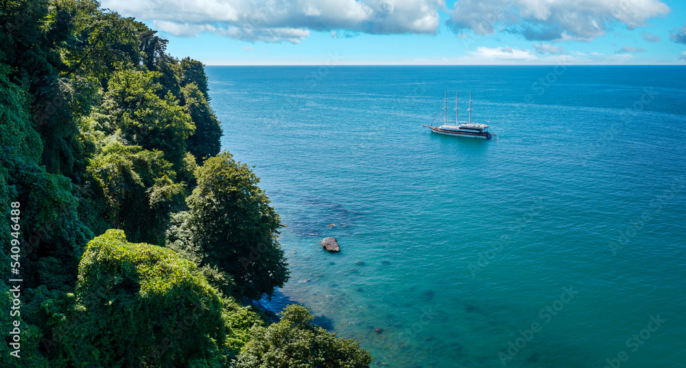 Aerial view of a sailing boat anchored off a rocky coast