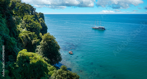 Obraz na płótnie Aerial view of a sailing boat anchored off a rocky coast w salonie