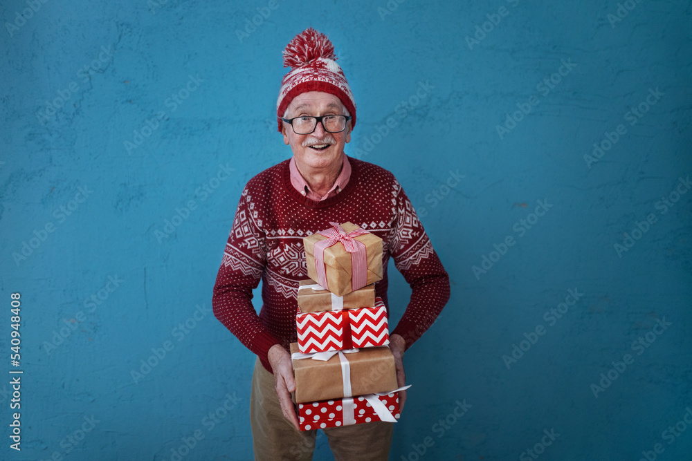 Portrait of happy senior man holding gifts, studio shooting.