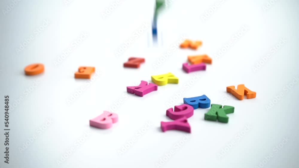 Spinning colored letters on a white table. Close-up conceptual shot of alphabet letters falling on a white background. Representing memory loss, brainstorming, writing, amnesia. Spinning colored letters on a white table. Close-up conceptual shot of alphabet letters falling on a white background. Representing memory loss, brainstorming, writing, amnesia.