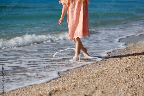 Girl child walking barefoot at sea beach