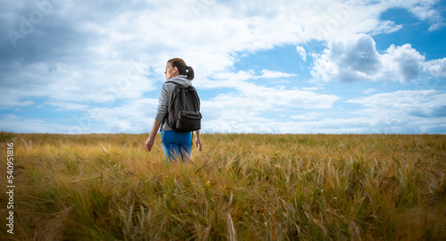 Woman with a backpack walking through a field, enjoying the countryside. © Rob Wilkinson