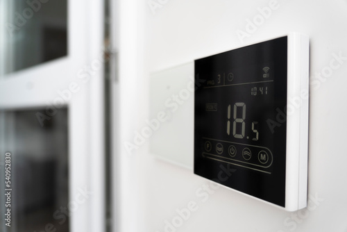 a device for controlling underfloor heating. air conditioner screen on wall that shows an air temperature of 18 degrees Celsius