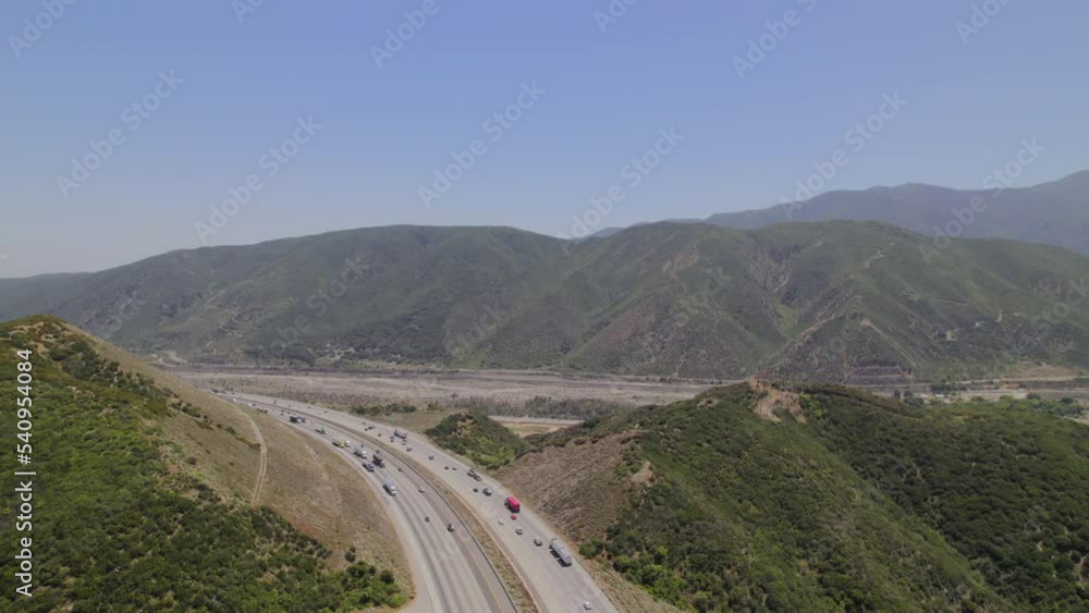Aerial view of the mountain highway in California. Traffic of interstate in mountain area with driving cars and trucks. Aerial view of the mountain highway in California. Traffic of interstate in mountain area with driving cars and trucks.