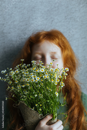 Red-haired girl with a bouquet of daisies