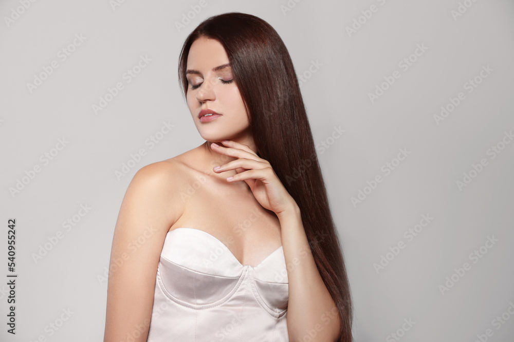 Portrait of beautiful young woman with healthy strong hair on light gray background, space for text Portrait of beautiful young woman with healthy strong hair on light gray background, space for text