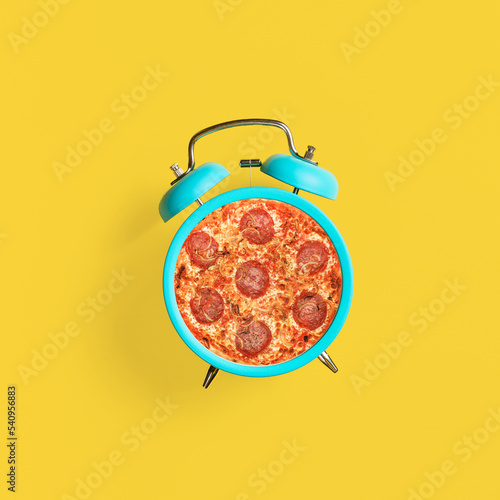 Turquoise vintage alarm clock on yellow background. Top view. Modern food concept.