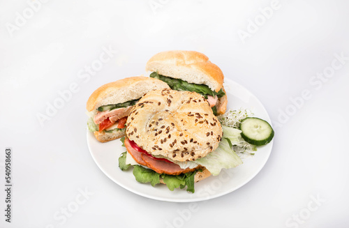 Sandwiches made of crunchy bread rolls, with fresh vegetables and Polish meat cold cuts, on a white plate, isolated.