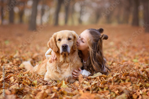 beautiful girl in the autumn park with a dog golden retriever labrador for a walk