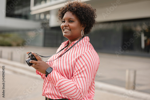Smiling young afro woman with retro photo camera