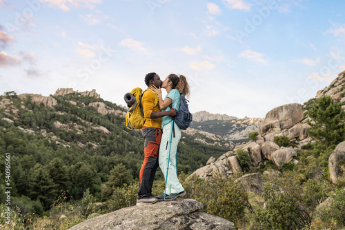 Young adult couple spending day in nature and kissing while hiking photo