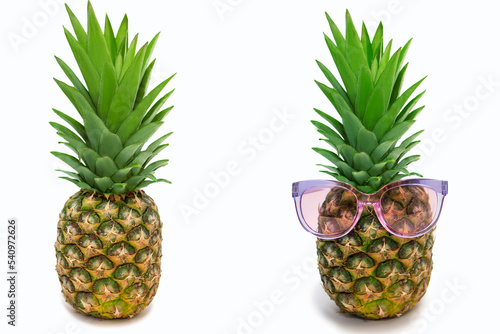 Two ripe pineapples on a white background. Plain pineapple and pineapple with sunglasses. The evolution of fashion in a fruity concept. Free space for text