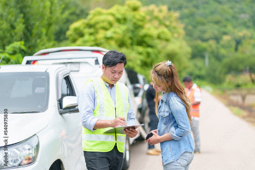 An insurance agent talking to a woman outside on the road after a car accident. An insurance agent talking to a woman outside on the road after a car accident.