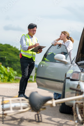 An insurance agent talking to a woman outside on the road after a car accident. © ND STOCK