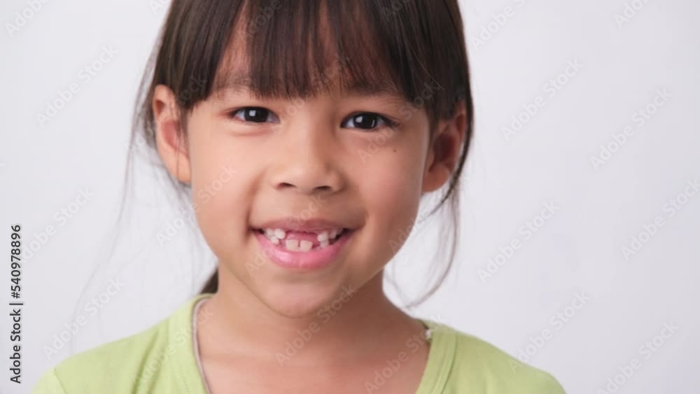 Portrait of an Asian girl with broken upper baby teeth and first permanent teeth. Friendly little girl showing her broken teeth isolated on white background. Portrait of an Asian girl with broken upper baby teeth and first permanent teeth. Friendly little girl showing her broken teeth isolated on white background.