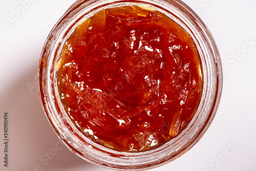 Fresh homemade orange marmalade in a glass jar on a white background. Top view.