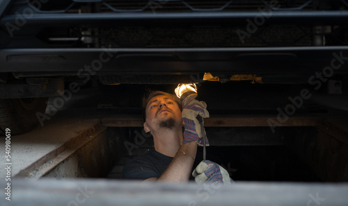 The mechanic services the car under the car