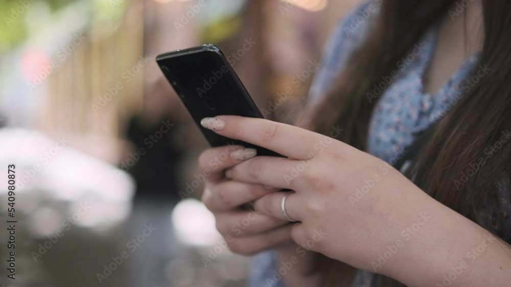 Women holding cell phone using smartphone device in a street cafe. Woman blogger subscribing new social media, buying in internet, ordering products online in apps. Women holding cell phone using smartphone device in a street cafe. Woman blogger subscribing new social media, buying in internet, ordering products online in apps.