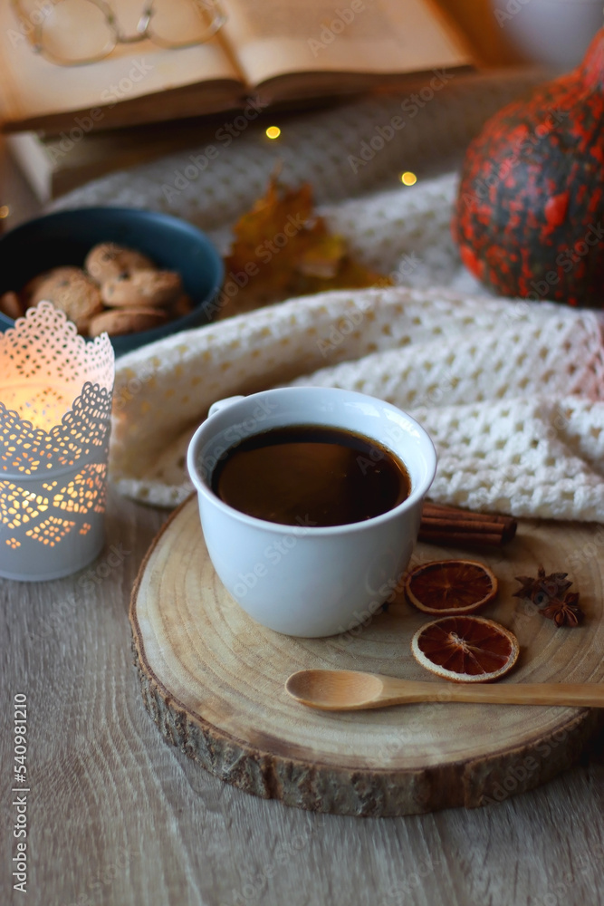 Cup of tea or coffee, seasonal spices, bowl of cookies, blanket, pumpkins, colorful leaves, books and candle. Cozy autumnal atmosphere at home. Selective focus. Cup of tea or coffee, seasonal spices, bowl of cookies, blanket, pumpkins, colorful leaves, books and candle. Cozy autumnal atmosphere at home. Selective focus.