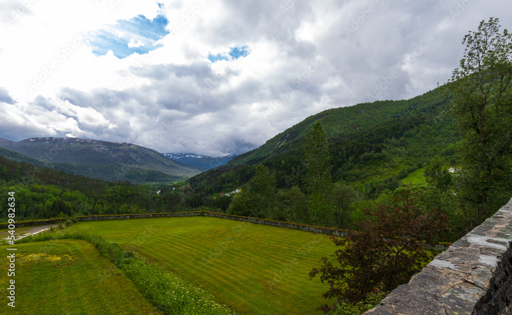 Naklejka premium Beautiful Lush Green Summer Mountain View Of The Naeroy Valley With Overcast Sky At Stalheim Hotel In Vossestrand, Western Norway.