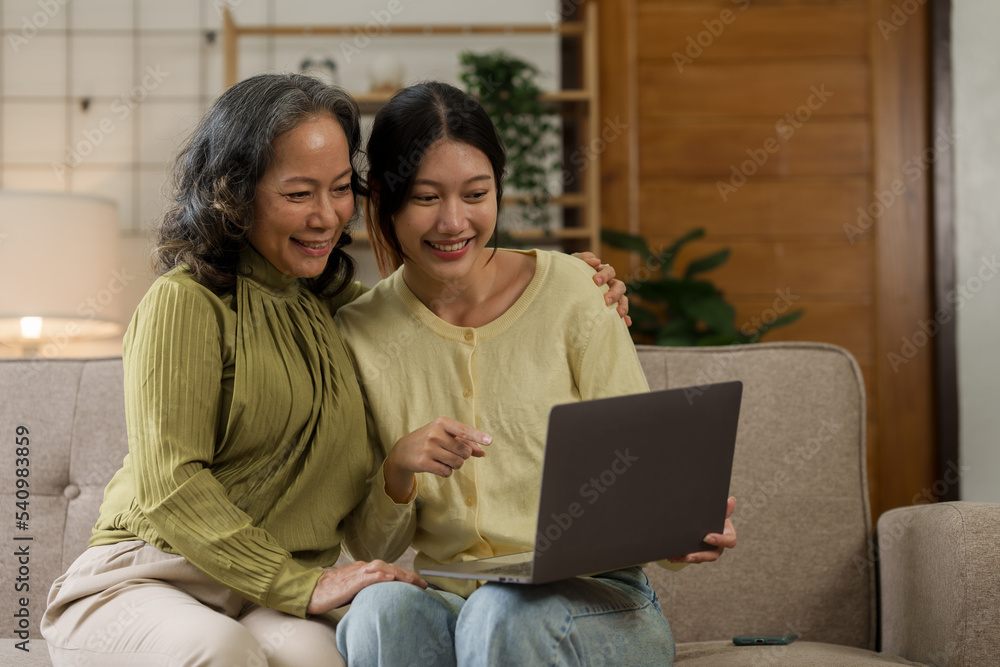 Asian mature woman hugging with daughter while sitting on sofa, mother day concept. Asian mature woman hugging with daughter while sitting on sofa, mother day concept.