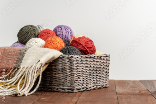 Multi-colored yarn in a basket on the table. Knitting concept. Hobby. Bright background with accessories for knitting.