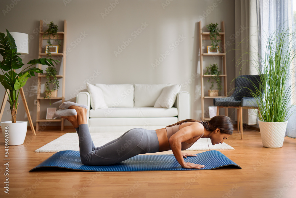 Young woman trains at home and does push-ups Young woman trains at home and does push-ups