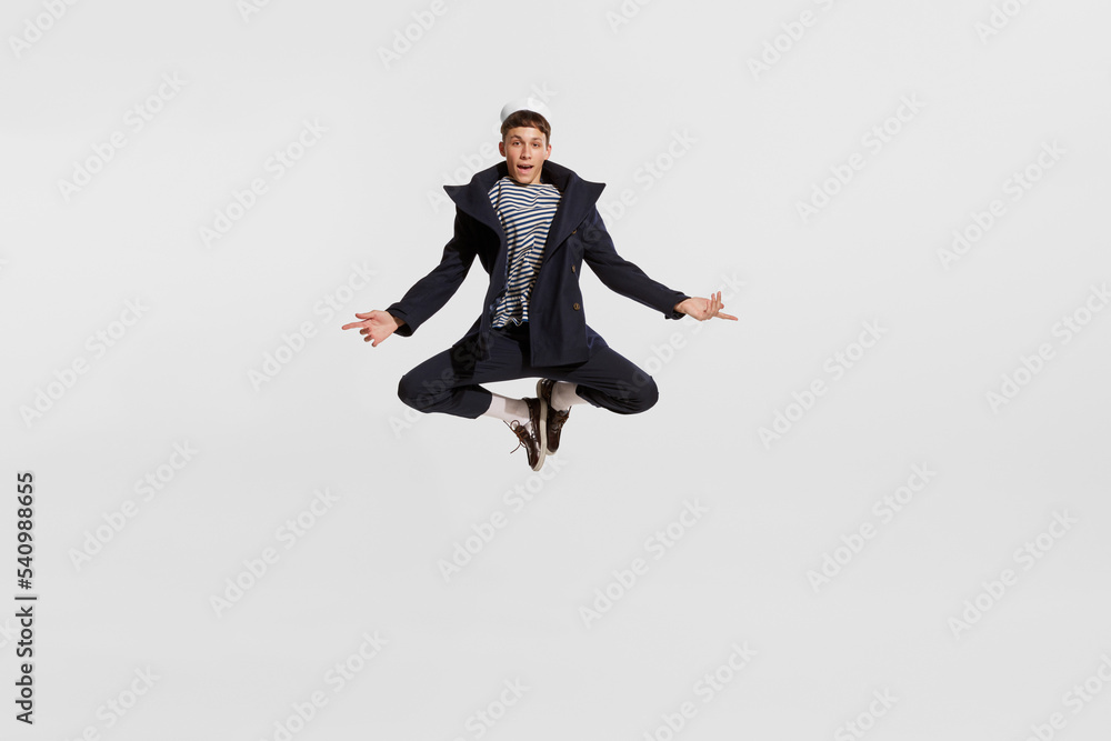 Portrait of young boy, sailor in striped shirt and jacket posing in a jump isolated over white background Portrait of young boy, sailor in striped shirt and jacket posing in a jump isolated over white background