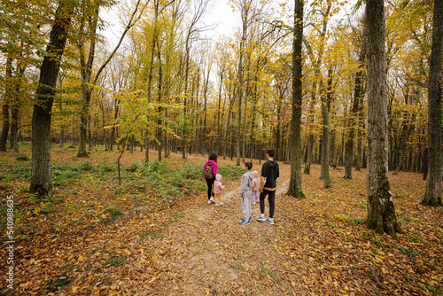 Mother with kids on a walk in autumn forest.