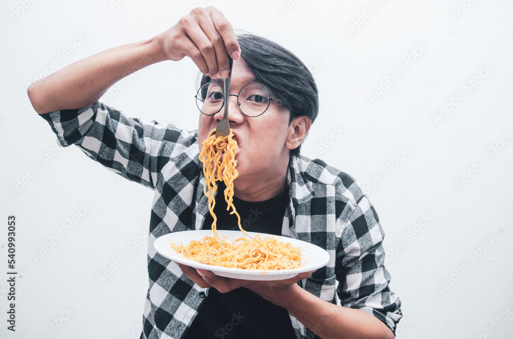 Portrait of Happy Asian man in casual shirt eats instant noodles using fork hungrily isolated over white background. Portrait of Happy Asian man in casual shirt eats instant noodles using fork hungrily isolated over white background.