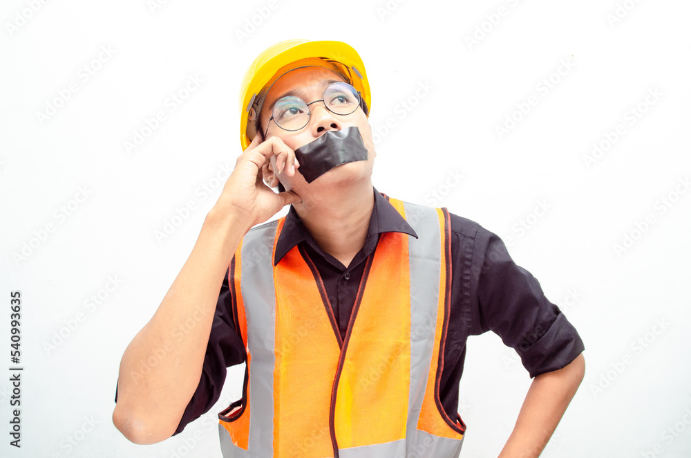 Young asian construction worker doing protest by covering mouth with tape isolated over white background. labour day concept. freeedom of speech concept. Young asian construction worker doing protest by covering mouth with tape isolated over white background. labour day concept. freeedom of speech concept.