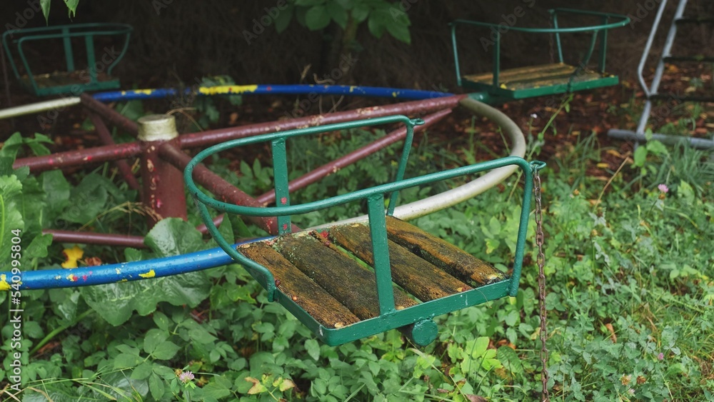 Creepy Abandoned Ruined Playground with Slide and Withered Wooden Seat on Rusty Metal Carousel