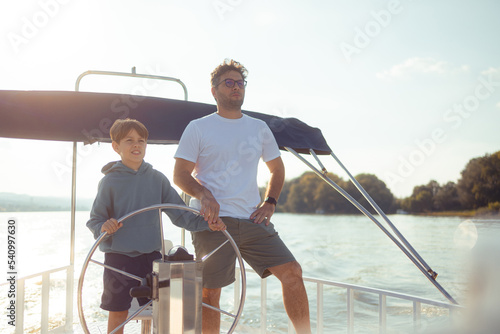 From a young age, the father teaches his son how to steer a ship. It's a nice sunny autumn day outside