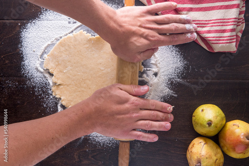 Cropped image of hands rolling dough photo