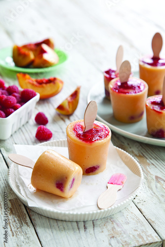 Close-up of raspberry and peach popsicles on table at home photo