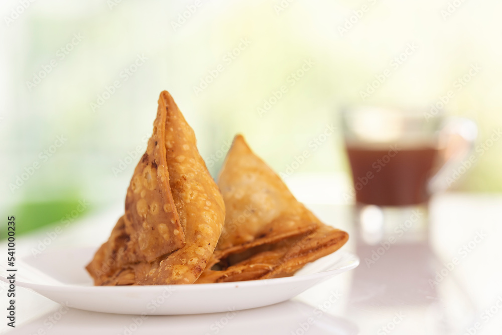 Plate of hot Samosas and cup of tea on table 