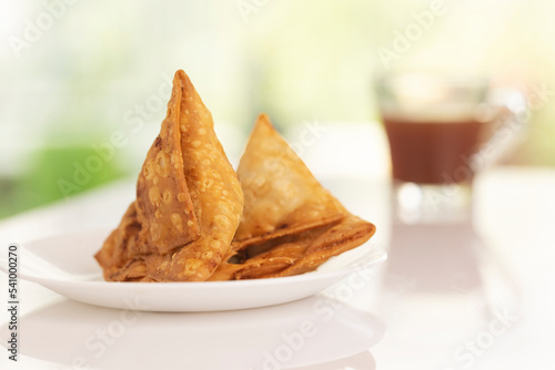 Plate of hot Samosas and cup of tea on table 