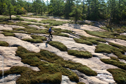 A man rides his mountain unicycle on exposed granite of the Cedar Rock Trail in the Dupont State Forest near Brevard, NC. photo
