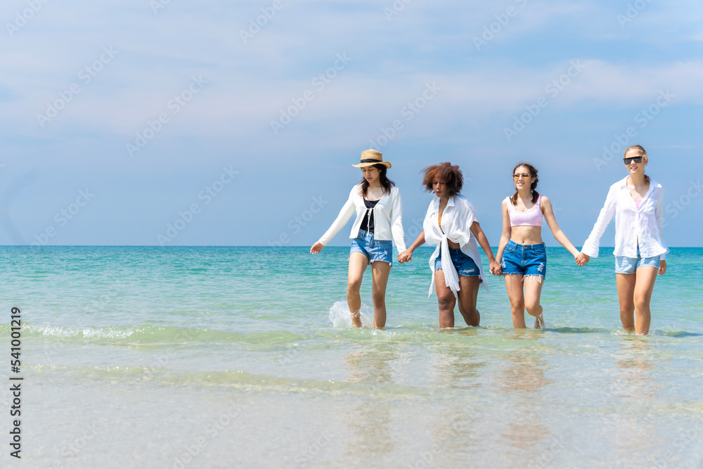 Photo of a group of girls of different ethnicities running and having fun together at the beach. on a fresh day