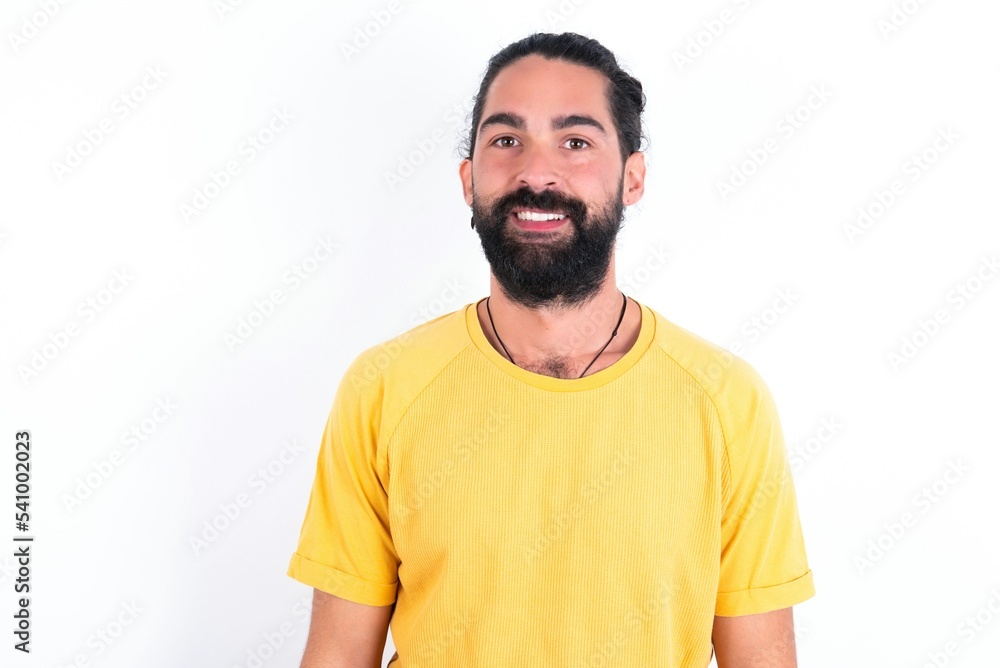 young bearded hispanic man wearing yellow T-shirt over white background with nice beaming smile pleased expression. Positive emotions concept young bearded hispanic man wearing yellow T-shirt over white background with nice beaming smile pleased expression. Positive emotions concept