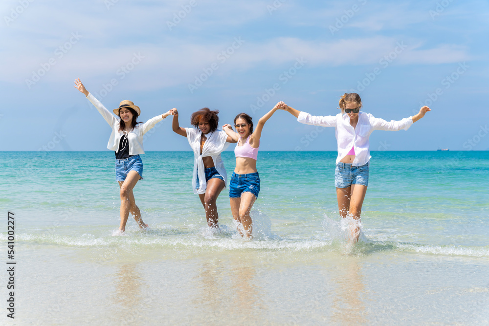 Photo of a group of girls of different ethnicities running and having fun together at the beach. on a fresh day Photo of a group of girls of different ethnicities running and having fun together at the beach. on a fresh day