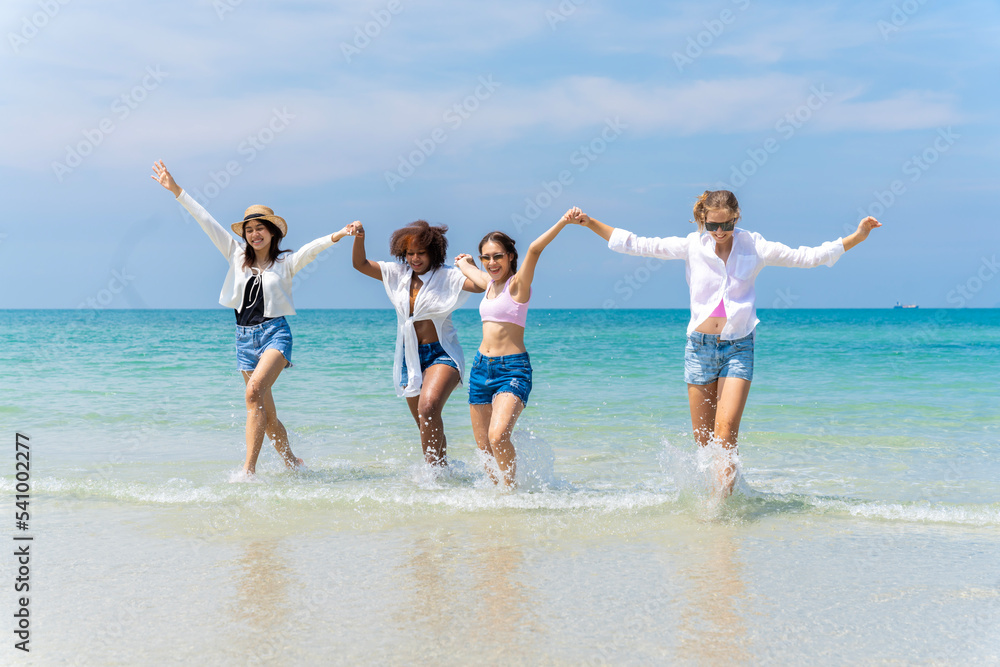 Photo of a group of girls of different ethnicities running and having fun together at the beach. on a fresh day