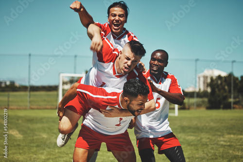 Soccer player, soccer and soccer field, winner and team, diversity and celebrate goal, athlete happy and sports win. Sport, fitness and young men celebrating, outdoor game and team spirit, piggy back © peopleimages.com