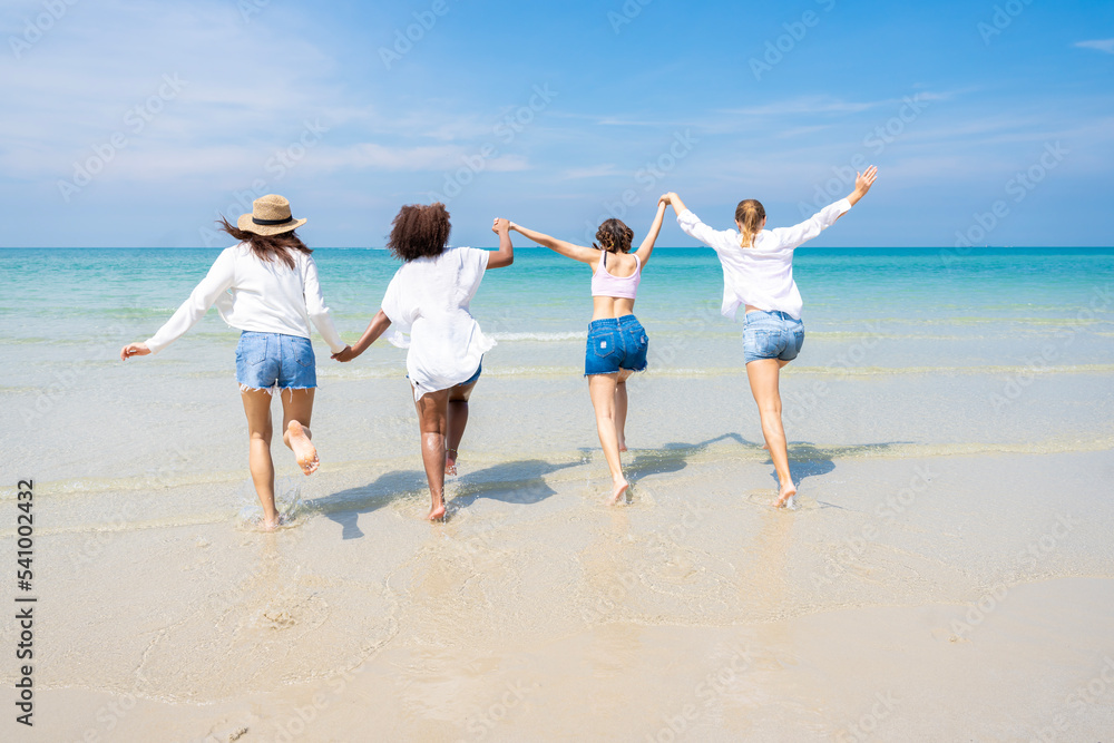 Photo of a group of girls of different ethnicities running and having fun together at the beach. on a fresh day Photo of a group of girls of different ethnicities running and having fun together at the beach. on a fresh day