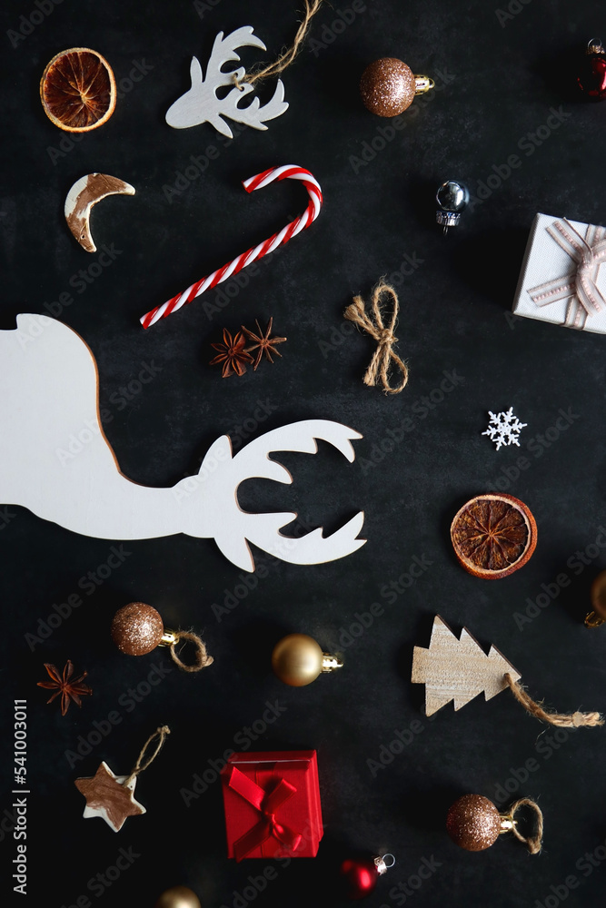 Small presents, various Christmas ornaments and deer figurine on dark background. Top view. Small presents, various Christmas ornaments and deer figurine on dark background. Top view.