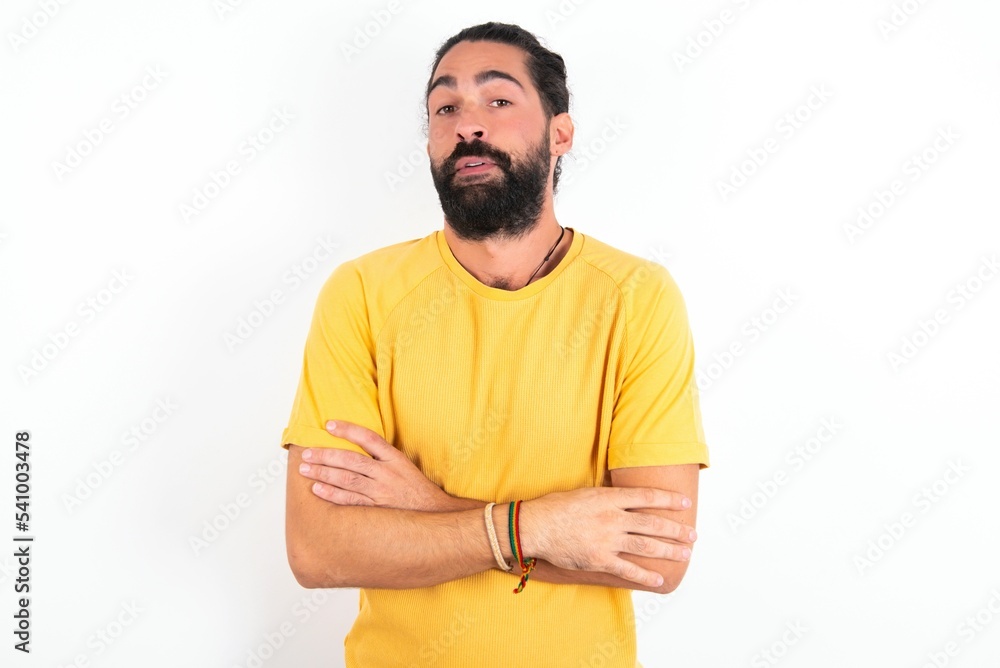 Fototapeta premium young bearded hispanic man wearing yellow T-shirt over white background shaking and freezing for winter cold with sad and shock expression on face.