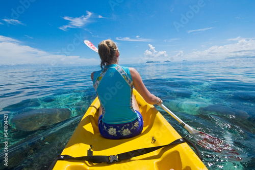 A woman paddling a Sit on Top Kayak to go snorkeling at the home reef of Tokoriki Island, Fiji. photo