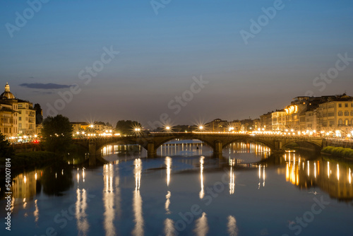 The Ponte Alla Carraia is illuminated at night over the Arno River in Florence, Italy. photo